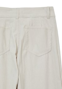 Pantaloni in corduroy color crema con texture a coste verticali, dotati di due tasche posteriori a toppa e un design di vita standard.
