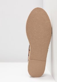 Semelle en caoutchouc marron texturé avec une légère courbure, présentant une surface à motifs. Les côtés de la chaussure sont en tissu à imprimé léopard avec une finition douce.