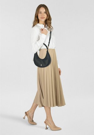 Borsa a tracolla in pelle nera con forma curva, tracolla regolabile e dettagli dorati, abbinata a una lunga gonna beige plissettata e tacchi color nudo.