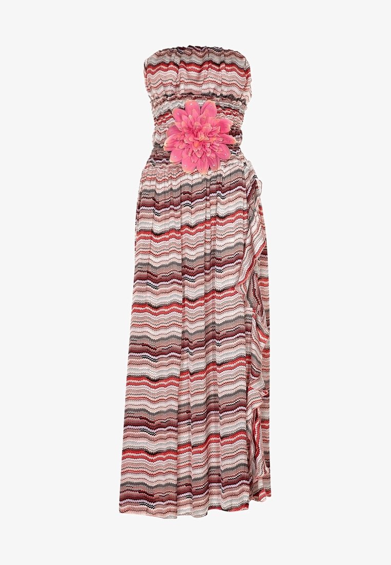 Strapless maxi-jurk met een multicolore zigzagpatroon in rood, roze en grijs, met een grote roze bloemenaccent bij de taille.