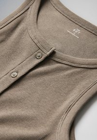 Ärmelloses, geripptes Stricktop in Hellbraun mit rundem Ausschnitt und zwei Knöpfen vorne, flach auf einer neutralen Oberfläche liegend.
