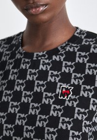 Μαύρη μπλούζα με επαναλαμβανόμενο γκρί σχέδιο "PKNY" και μικρό κεντητό λογότυπο με κόκκινες και λευκές λεπτομέρειες. Σχέδιο με λαιμόκοψη τύπου crew neck.
