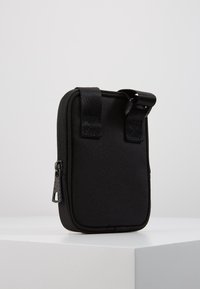 Czarna saszetka na zamek wykonana z trwałego materiału, z dwoma materiałowymi paskami u góry, prostokątny kształt, gładka tekstura, bez widocznych wzorów.