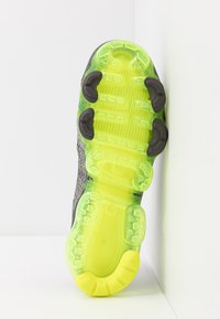 Podeszwa buta z elastycznym wzornictwem, z przezroczystą, jasną żółtą sekcją, teksturowanymi uchwytami oraz ciemną górną częścią dla stabilności.