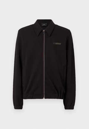 Črna jakna s ovratnikom, sprednjim zadrgo, ki ima barvite detajle, ter elastičnimi manšetami in robom. Vključuje diskretne akcentne logotipe.