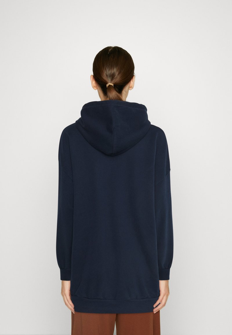 Sweat à capuche bleu marine avec des manches longues, une coupe décontractée et des poignets côtelés, fabriqué en tissu doux. La vue de dos montre un detailing minimal.