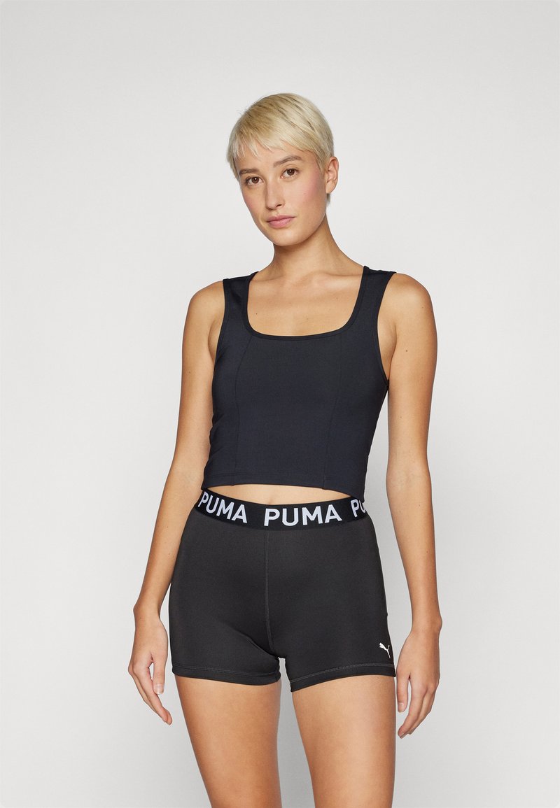 Crni crop top s kvadratnim izrezom, uparen s crnim šortsevima koji imaju struk s bijelim Puma logotipom, izrađen od rastezljivog, atletskog materijala.