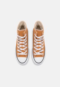 Zapatillas altas de lona naranja con cordones blancos, suela de goma negra contrastante y puntera reforzada. Diseño simple y clásico.