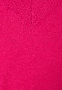 Maglione fucsia a V con un motivo a maglia testurizzato, caratterizzato da un design a V profonda e tessuto liscio. Materiale morbido e leggero.