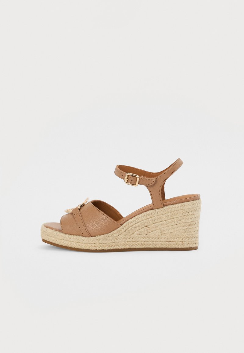 Sandales compensées en cuir marron avec une semelle en jute tressé. Comprend une bride de cheville avec une boucle en métal et deux brides croisées à l'avant.