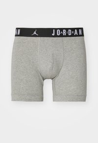 Grå bomuldsboksershorts med en sort elastisk talje, der har ordet "JORDAN" og et logo i hvid. Mellemlang design med tætsiddende pasform.
