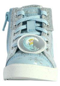Sneaker azzurro chiaro con dettagli argentati luccicanti, logo rotondo che presenta un personaggio e motivi di fiocchi di neve su materiale sintetico.