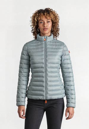 Gevoerde lichtblauwe ritsjack met een staande kraag, voorzien van een horizontaal gewatteerd patroon, elastische manchetten en een oranje ritstrekker.
