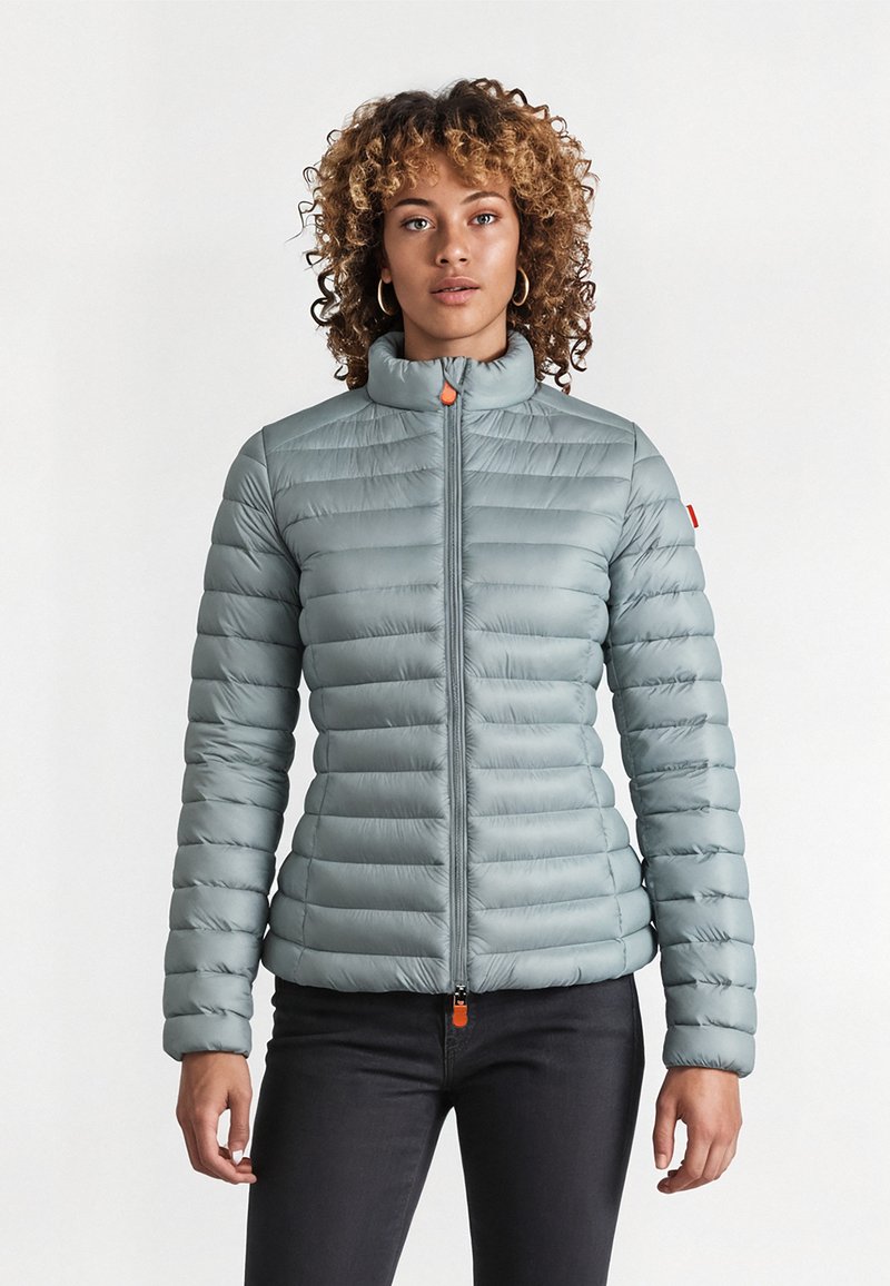 Gevoerde lichtblauwe ritsjack met een staande kraag, voorzien van een horizontaal gewatteerd patroon, elastische manchetten en een oranje ritstrekker.
