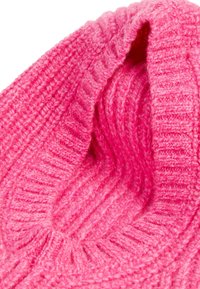 Rosa strikket scarf, der viser ribbet tekstur. Tyk garn skaber et hyggeligt udseende med et foldet design og blød finish.