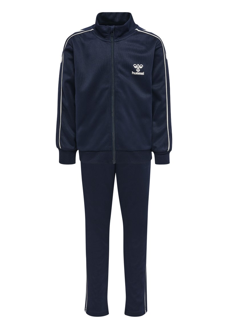 Chándal azul marino hecho de tejido ligero. Presenta una chaqueta con cremallera y cuello alto, y rayas blancas en los laterales. Incluye pantalones a juego.