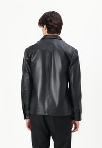 Must must jacket sileda viimistlusega, klassikaline krae ja sirge lõige. Omab pikki varrukaid ja minimalistikku disaini.