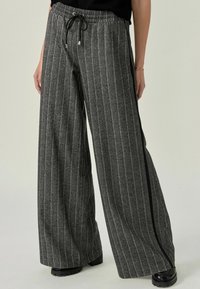 Graue gestreifte High-Waist-Hosen mit elastischem Bund, Kordelzug und seitlichem Akzentstreifen. Hergestellt aus weichem Material mit strukturiertem Finish.