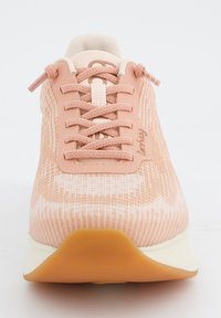 Baskets de sport rose clair avec une tige en tissu textur é, lacets à l'avant et accents blancs. Semelle en caoutchouc légèrement courbée pour le soutien.