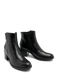 Botas de tobillo de cuero negro con un diseño elegante, que cuentan con una cremallera lateral, tacón bajo y una textura suave.