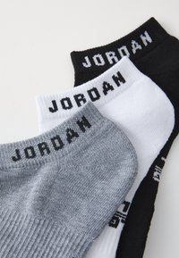 Kolme paria nilkkasukkia mustana, valkoisena ja harmaana. Jokaisessa on ribatti rakenne ja siinä on "JORDAN" painettuna varsiin.