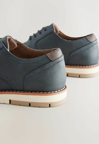 Dark blue leather shoes with rounded toes, light brown insoles, contrasting stitching, and white soles. Features a smooth texture and simple design.