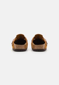 Brune semskede slip-on sandaler med korksåler, med teksturerte bak- og sidestriper. Åpen design for god lufting.