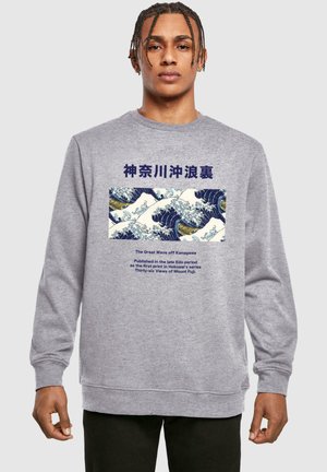 Grå sweatshirt med et stort tryk af "Den Store Bølge ved Kanagawa" med blå og hvide bølger, accentueret af marineblå tekst over og under billedet.