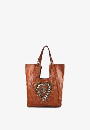 Bruine leren totebag met twee handvatten en een decoratief hartvormig ontwerp van metalen studs en munten aan de voorkant.