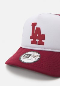 Κόκκινο και λευκό καπέλο μπέιζμπολ με ανάγλυφο λογότυπο "LA", ρυθμιζόμενο λουράκι και στρογγυλή ετικέτα New Era στο πλάι. Υποπλάστης με υφαντή υφή.
