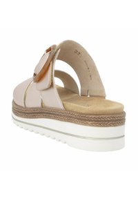 Sandale rose clair avec une texture douce semblable au daim, accent circulaire beige, design ouvert et semelle blanche texturée avec un détail tissé brun.