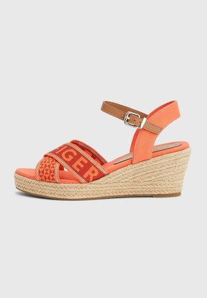 Orange kile sandaler med en vævet jute-sål, der har krydsede stropper i mønstret stof og en justerbar ankelrem i brunt.