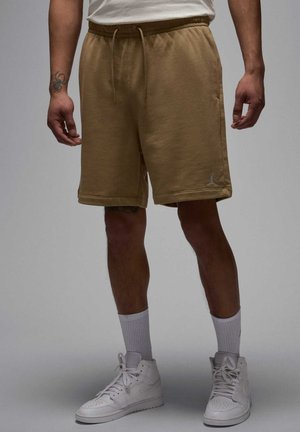 Beige bomulds shorts med elastisk talje, sidelommer og et lille logo på venstre ben. Sat sammen med hvide høj-til-top sneakers og sokker.