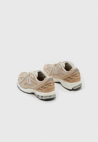 Beige og kremfargede sneakers med et teksturert mesh-overdel, reflekterende detaljer og en dempet såle. Har et "N"-logo og formerte detaljer.