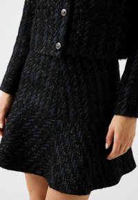 Giacca testurizzata con motivo a quadri nero e blu, dal design corto, con bottoni argentati lucidi e gonna leggermente svasata.