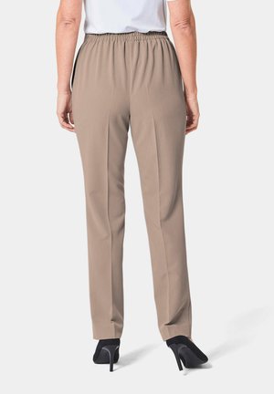 Beige, elastische taillebroek met een rechte pasvorm en een voorplooidetail, gecombineerd met zwarte hoge hakken, gezien van achteren.