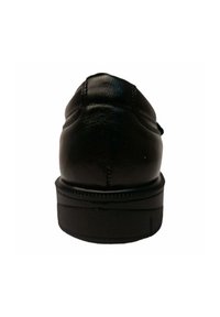 Zapato de cuero negro con punta redondeada, con costuras decorativas y suela plana de goma. El tacón es ligeramente elevado y redondeado.