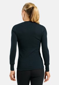 Dark navy long-sleeve top made from ribbed material, featuring a round neckline and fitted design, with visible stitching details along sleeves.