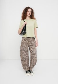 Ανοιχτό πράσινο κοντομάνικο μπλουζάκι συνδυασμένο με φαρδιές, ψηλόμεσες παντελόνες λεοπάρ. Μαύρη τσάντα ώμου και μαύρα αθλητικά παπούτσια ολοκληρώνουν το ντύσιμο.