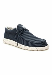 Zapatos a rayas en navy con un upper de tela texturizada, con punta redonda, diseño con cordones y una suela blanca salpicada.