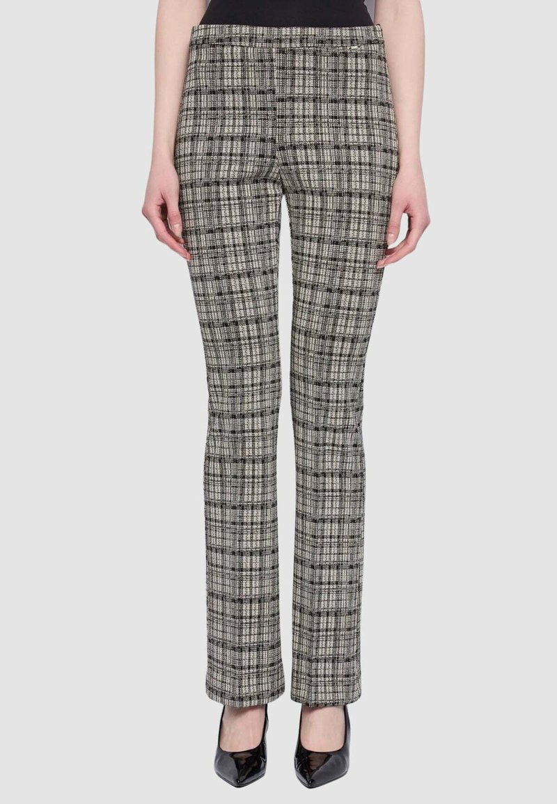 Pantaloni a quadri bianchi e neri con una vestibilità aderente, caratterizzati da un design a gamba dritta e una texture liscia. Indossati con tacchi alti.