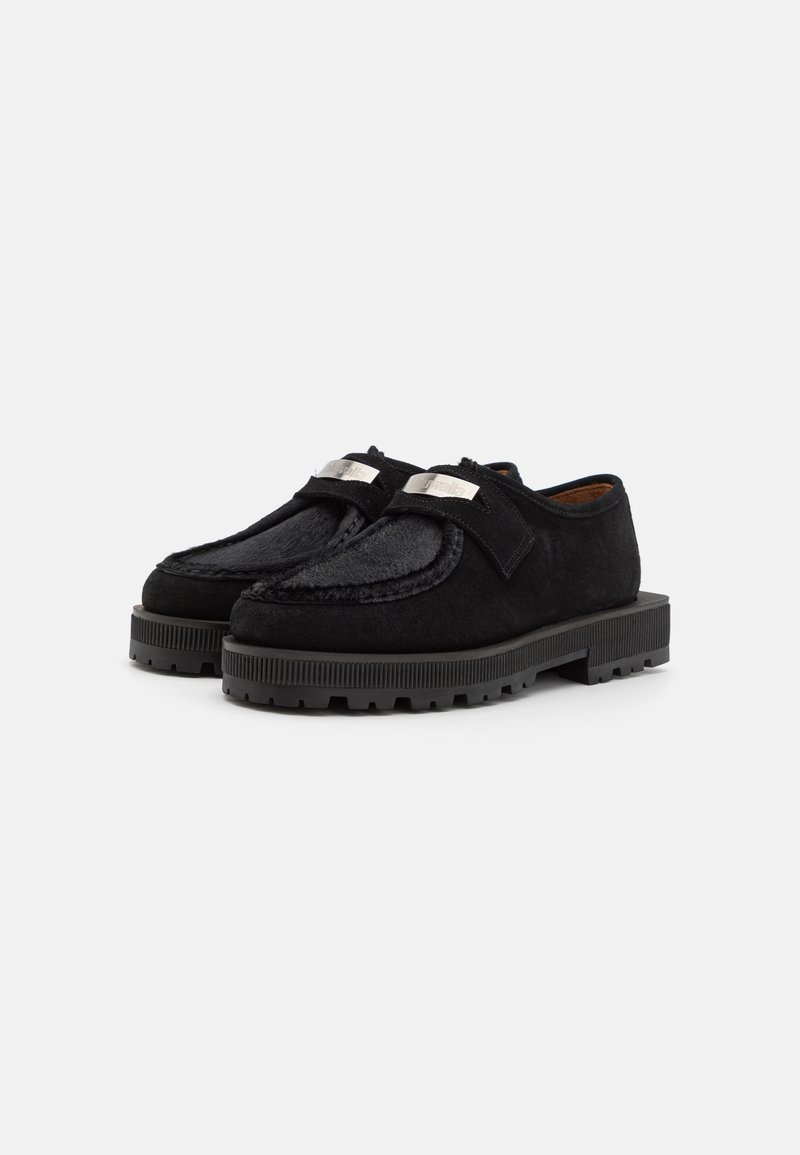 Chaussures noires en daim avec un upper lisse et texturé. Dotées d'une semelle noire épaisse et d'accents en métal argenté.