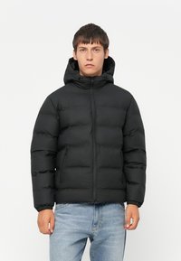 Doudoune noire avec capuche, dotée d'une fermeture éclair à l'avant, de poignets élastiques et de deux poches latérales. Texture lisse et design matelassé.