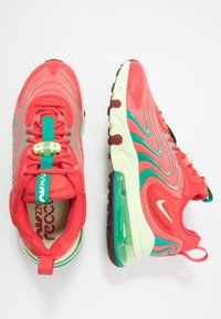 Ett par ljusa korall- och teal Nike Air Max 270 React sneakers, som visar uppifrån på vänstra skon och från sidan på högra skon mot vit bakgrund.