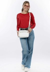 Borsa a tracolla bianca con tasca con zip, texture in pelle liscia. Top rosso a maniche lunghe, jeans a palazzo blu, sneakers bianche. Sfondo in luce naturale.