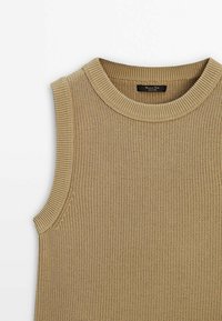 Beige värisetön ilman hihoja neulepaita, jossa on pyöreä ribbe-olka ja teksturoitu kuvio. Valmistettu pehmeästä, joustavasta materiaalista.