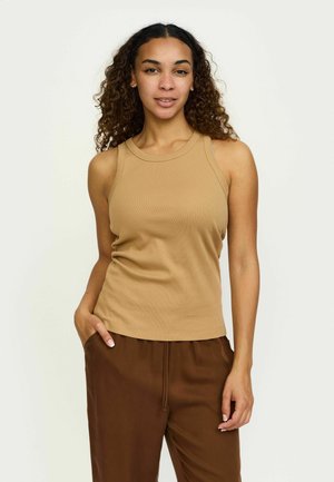 Svetlá bezramienková tielko z rebrového materiálu s okrúhlym výstrihom a priliehavým strihom, spárované s voľnými hnedými nohavicami.