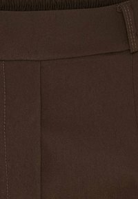 Brune stofbukser med flad front, elastisk talje og synlige syningsdetaljer; lavet af et blødt, struktureret materiale.