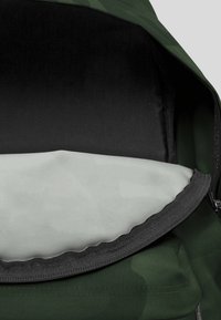 Mochila de camuflaje verde con apertura con cremallera, que presenta un exterior texturizado y un forro interior negro para contraste.
