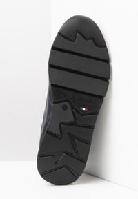 Suela de zapato de goma negra con un patrón de banda de rodadura en zigzag, con un logo que incluye "NeroGiardini" y acentos de la bandera italiana, además de detalles moldeados.